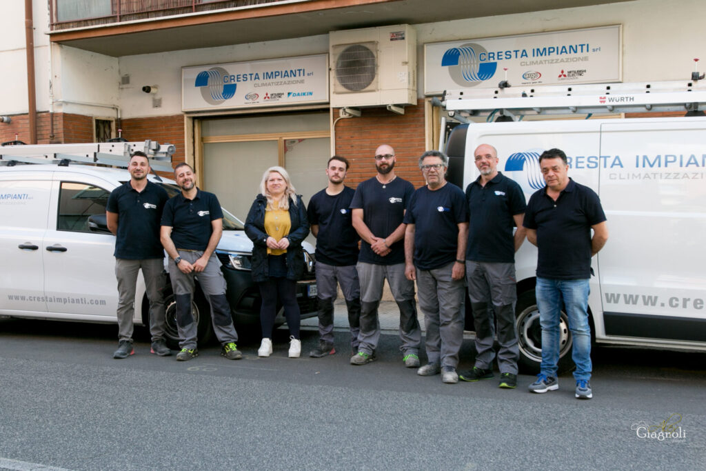 Gruppo di persone davanti a furgoni aziendali.