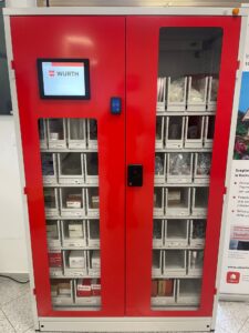 Distributore automatico rosso con scomparti e schermo digitale.