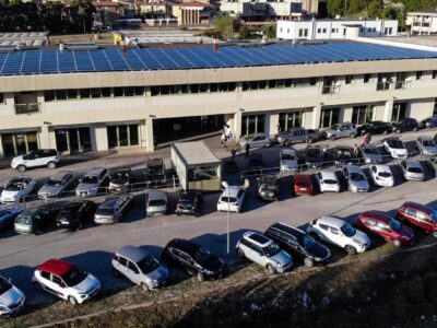 Parcheggio affollato davanti a un edificio con pannelli solari.