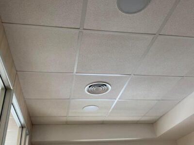 Soffitto con pannelli quadrati e bocchetta di ventilazione.