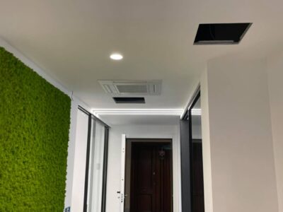 Corridoio moderno con parete verde e luci a soffitto.