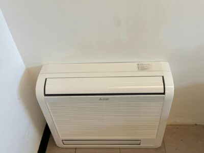 Condizionatore a parete bianco su pavimento piastrellato.