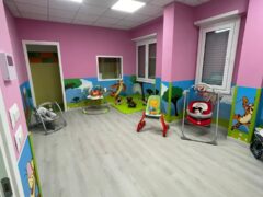 Stanza per bambini con pareti rosa e giochi colorati.