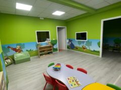 Aula per bambini con tavoli colorati e decorazioni murali.