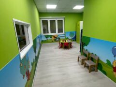 Aula per bambini con pareti verdi e decorazioni colorate.