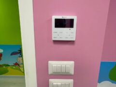 Termostato e interruttori su parete rosa con decorazioni.