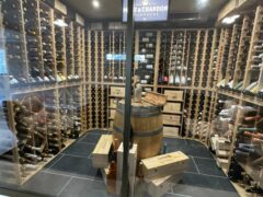 Cantina con bottiglie di vino e casse di legno.