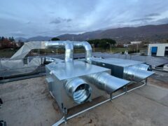 Impianto di ventilazione su un tetto con sfondo montuoso.
