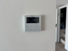 Termostato digitale su parete bianca, temperatura impostata 25&deg;C.