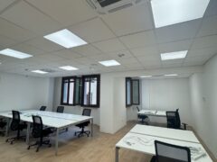 Ufficio moderno con scrivanie bianche e sedie nere.