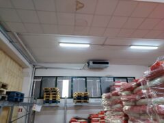 Magazzino con pallet, sacchi e macchie sul soffitto.