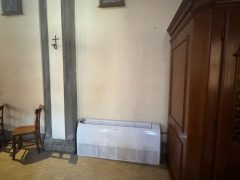 Interno di una chiesa con condizionatore e arredi religiosi.