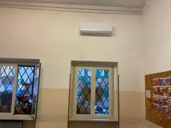 Aula con finestre, tavolo e condizionatore a parete.