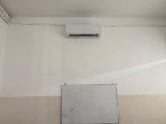 Aula con condizionatore, lavagna bianca e banchi.