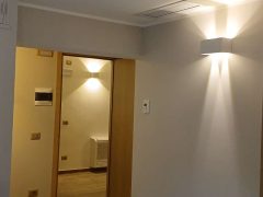 Corridoio interno con pavimento in legno e illuminazione moderna.