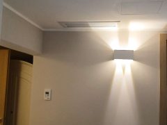 Parete interna con lampada accesa e griglia di ventilazione.