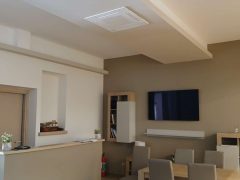 Interno moderno con tavolo, sedie e televisore a parete.