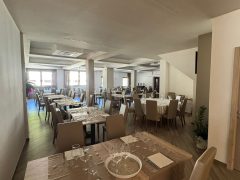 Sala ristorante con tavoli apparecchiati e sedie beige.