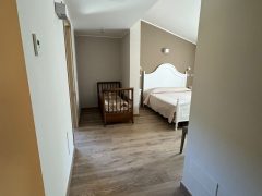 Corridoio verso camera da letto con culla e letto.