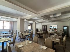Ristorante elegante con tavoli apparecchiati e sedie beige.