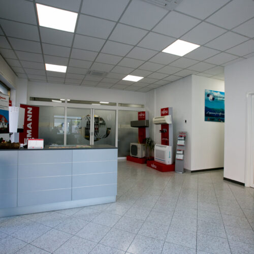 Interno di un ufficio moderno con reception e espositori.