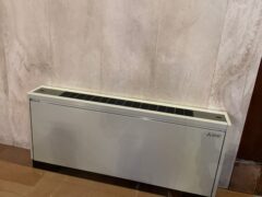 Riscaldatore bianco su pavimento in piastrelle marroni.