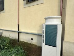 Unit&agrave; esterna di condizionamento vicino a edificio beige.
