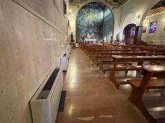 Interno di una chiesa con banchi e affreschi.