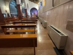 Interno di una chiesa con banchi e vetrate colorate.