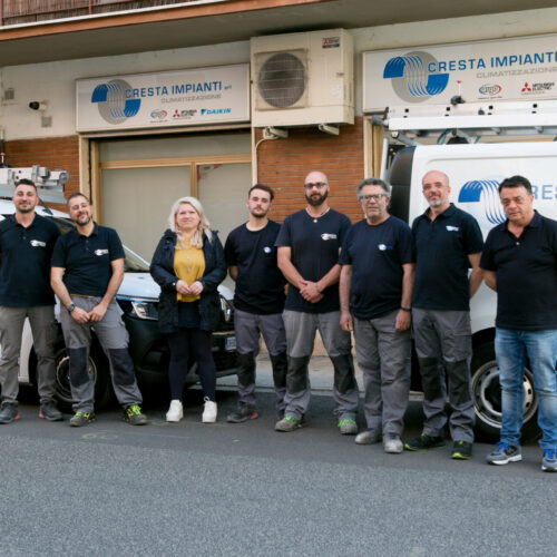 Gruppo di persone davanti a furgoni aziendali.