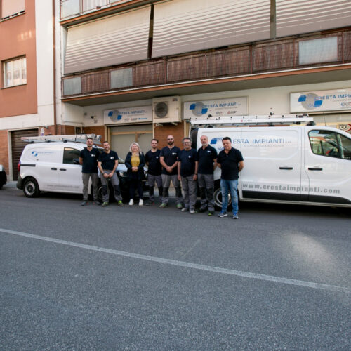 Gruppo di persone davanti a furgoni aziendali parcheggiati.