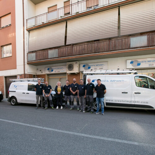 Gruppo di persone davanti a furgoni aziendali parcheggiati.