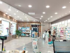 Interno di una farmacia con scaffali e persone.