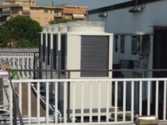 Unit&agrave; di condizionamento su un tetto, con ringhiera bianca.