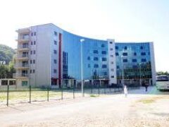 Edificio moderno con facciata in vetro e autobus parcheggiato.