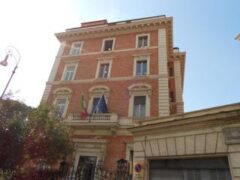 Edificio in mattoni con bandiere su balcone.