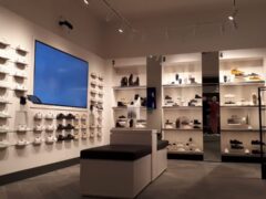 Negozio di scarpe con espositori e sedute centrali.