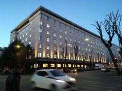 Edificio illuminato di sera con auto in movimento.