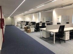 Ufficio moderno con scrivanie e sedie vuote.