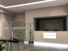 Reception moderna con tornelli e logo colorato sul bancone.