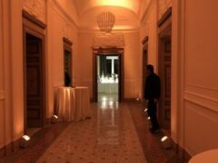 Corridoio elegante con illuminazione soffusa e tavoli rotondi.