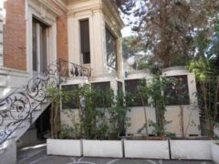 Scala esterna con ringhiera decorata e piante in vaso.