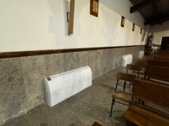 Interno di una chiesa con panche e condizionatore.
