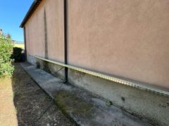 Parete esterna di un edificio con canalina e tubo.