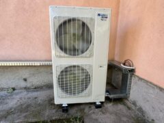 Unit&agrave; esterna di condizionamento accanto a muro rosa.
