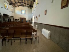 Interno di una chiesa con panche e vetrate colorate.