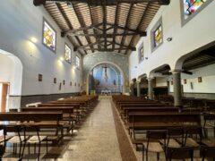 Interno di una chiesa con panche e vetrate colorate.