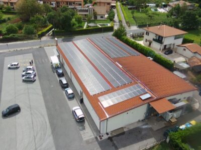 Edificio con pannelli solari sul tetto, parcheggio adiacente.